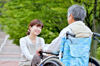caregiver smiling at elderly man in a wheelchair